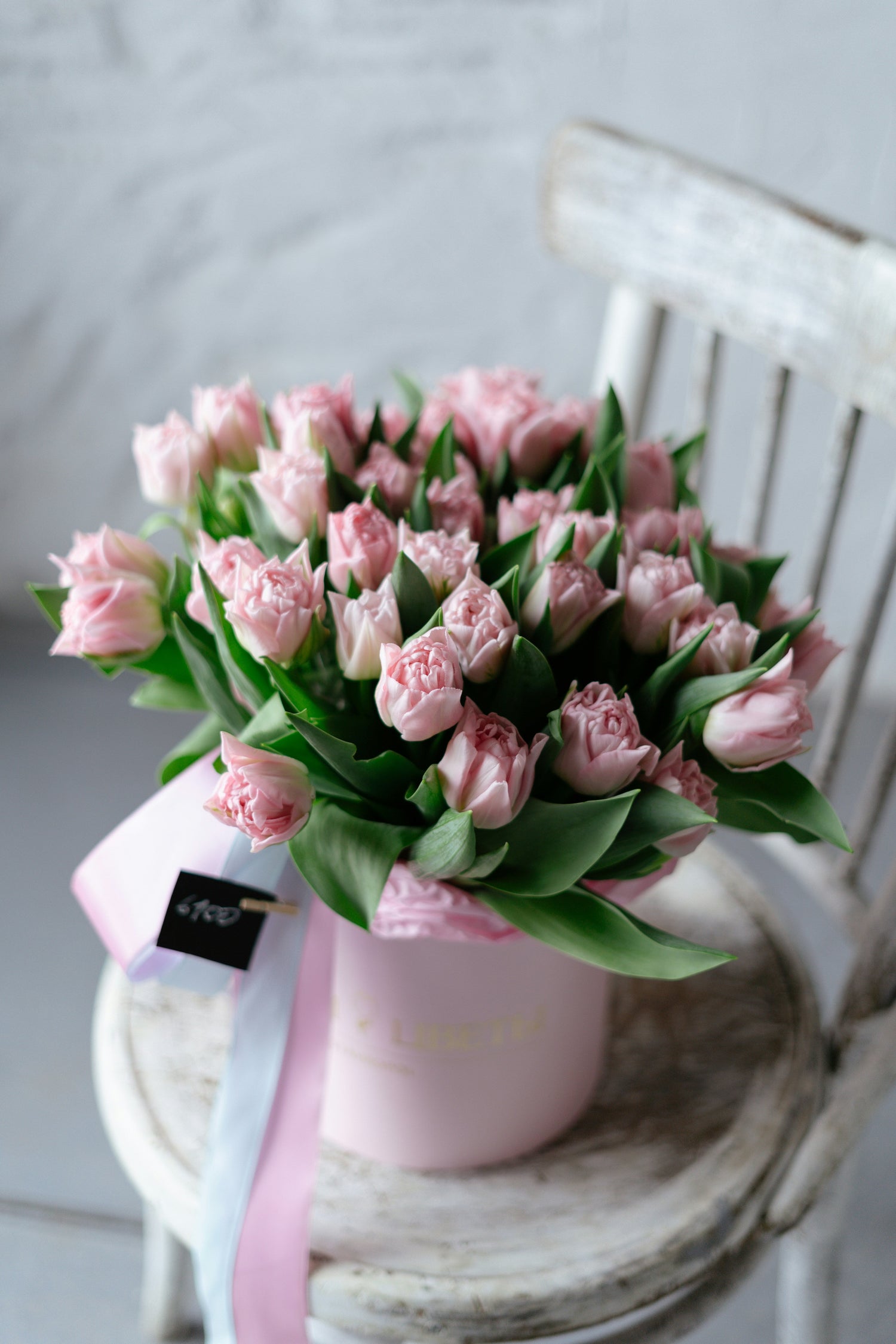 Fresh pink flowers in a vase on a wooden chair.