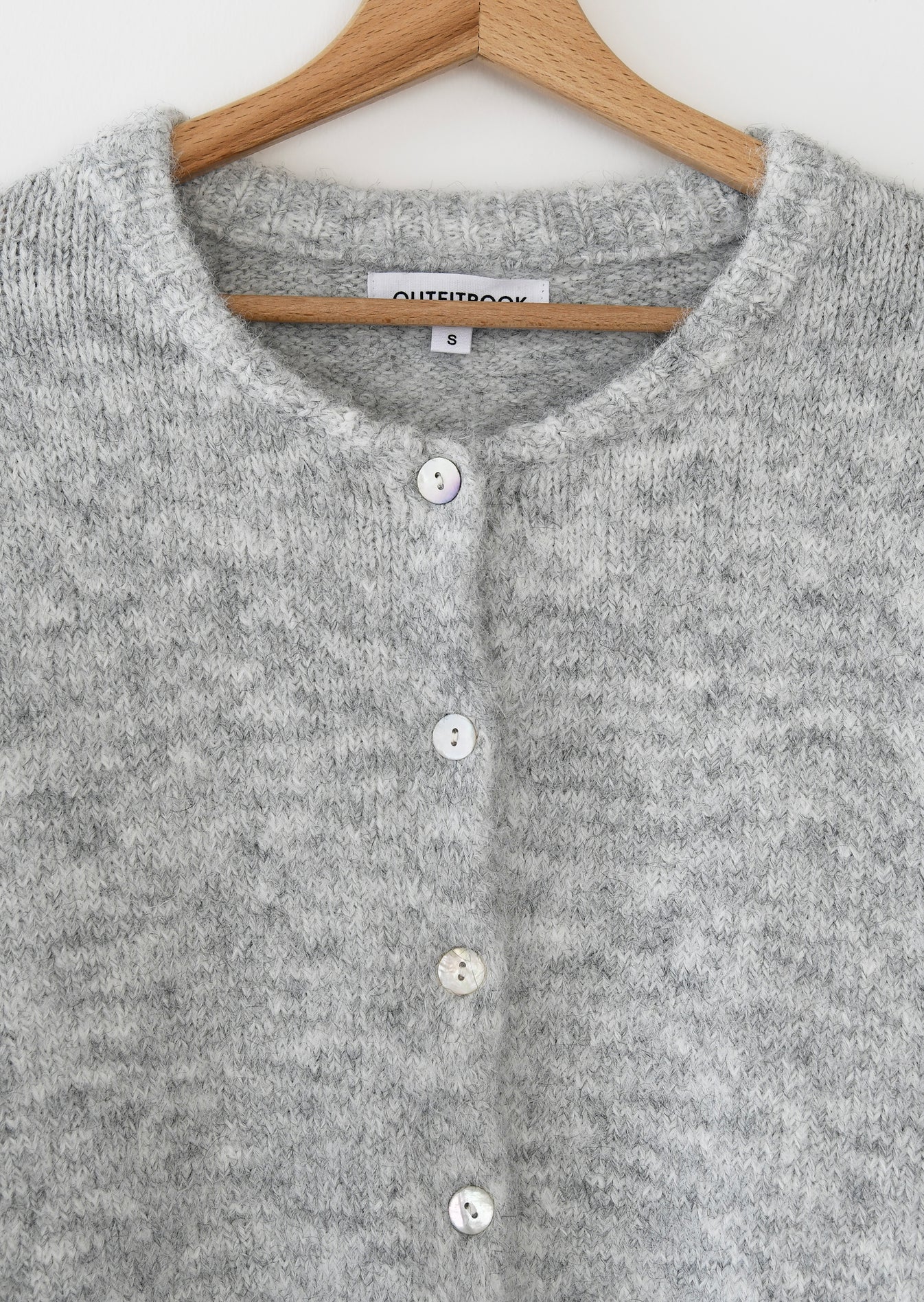 Gray cardigan with buttons on a wooden hanger