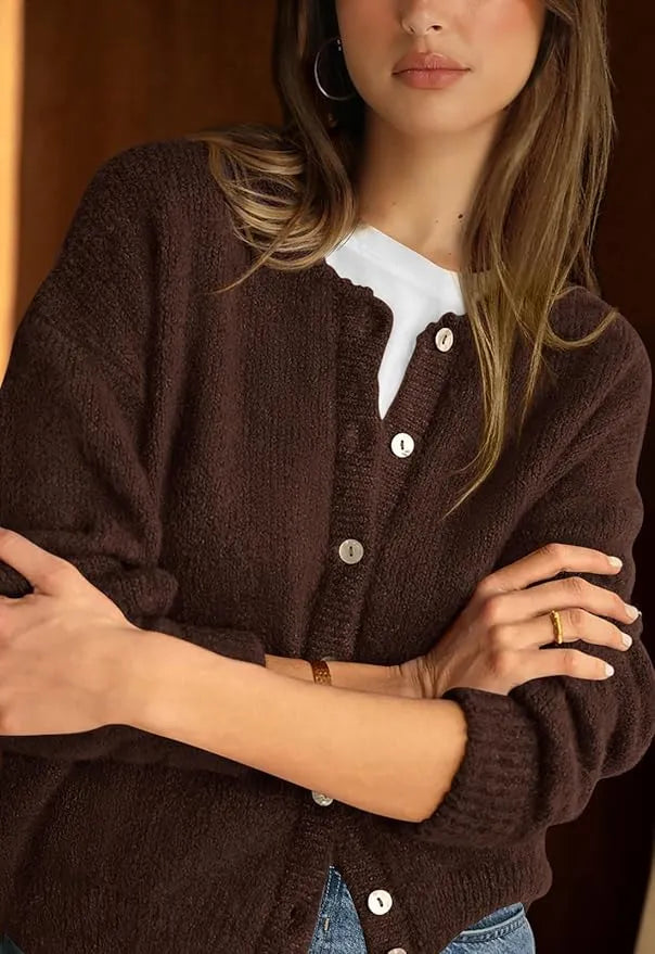 Woman wearing a brown cardigan with button details against a dark background