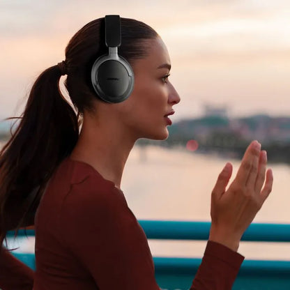 Woman wearing headphones by a waterfront at sunset