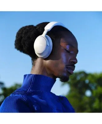 Person wearing white headphones with a blue sky and greenery in the background