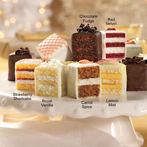Assorted slices of layered cakes on a white cake stand with labeled flavors.