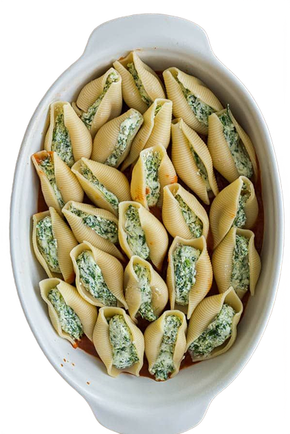 Pasta shells filled with a green filling in a white baking dish on a white background