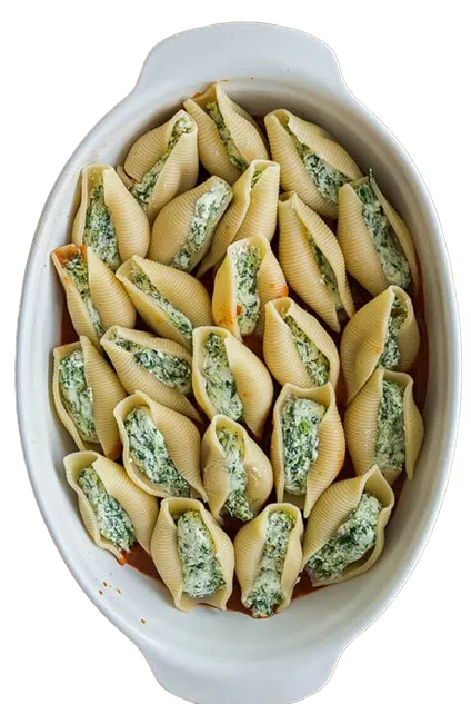 Pasta shells filled with a green filling in a white baking dish on a white background