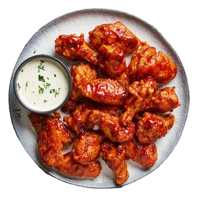 Platter of spicy wings with a side of ranch dressing on a white background
