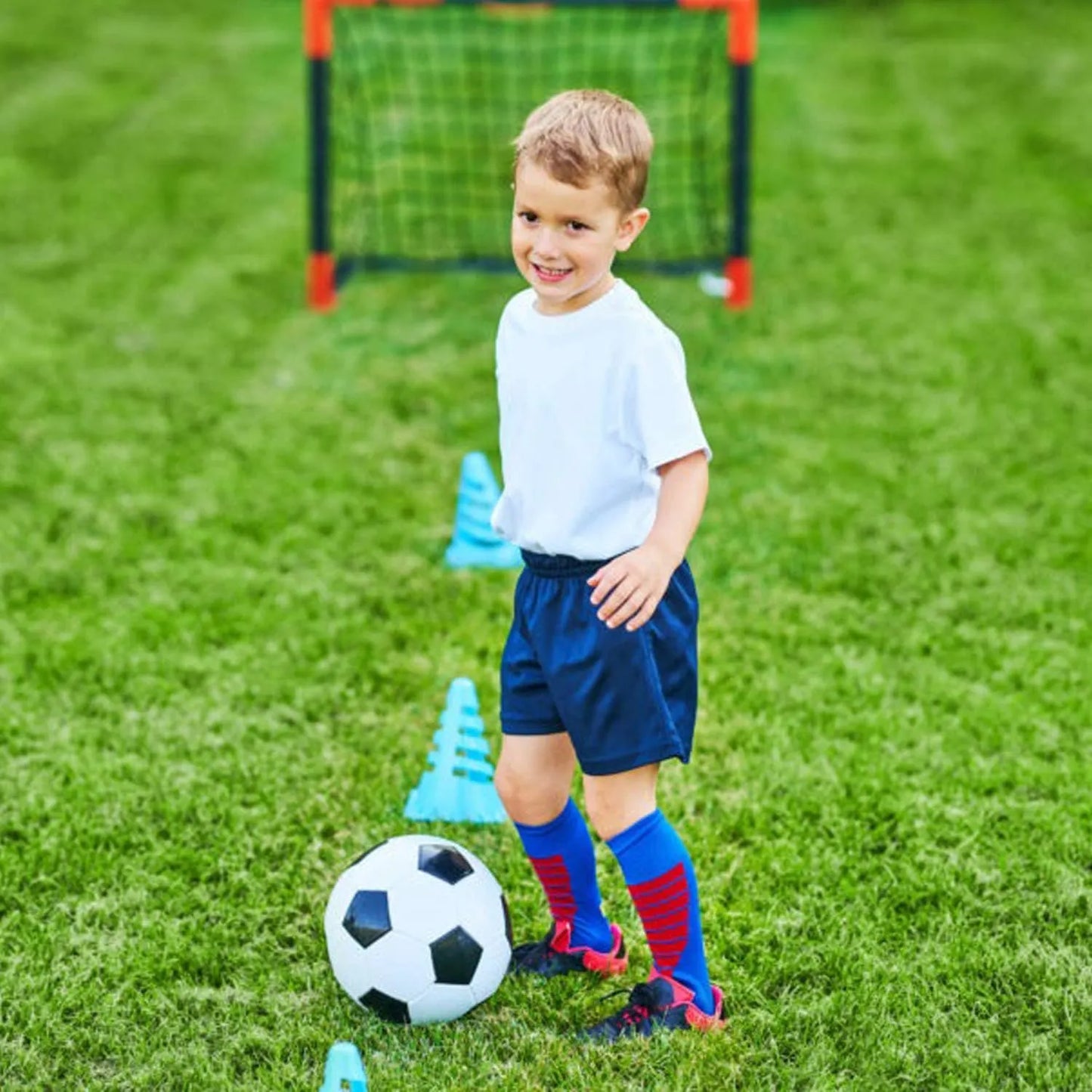 Young boy on a soccer field with a ball and cones