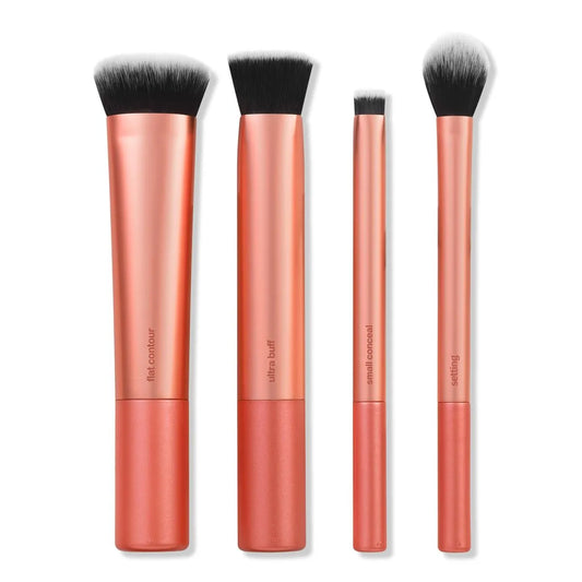 Set of four makeup brushes with rose gold handles on a white background
