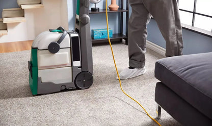 Person using a carpet cleaning machine in a living room.