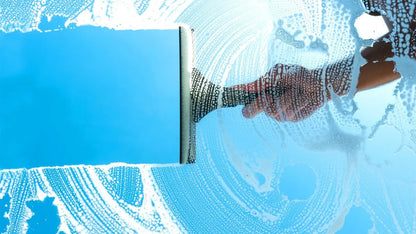 Squeegee cleaning a window with soap suds on a blue background