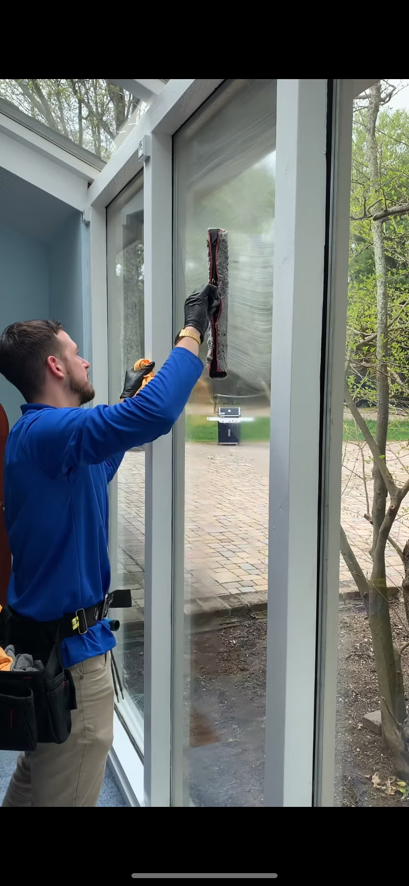 Person cleaning a window with a squeegee outside a building.