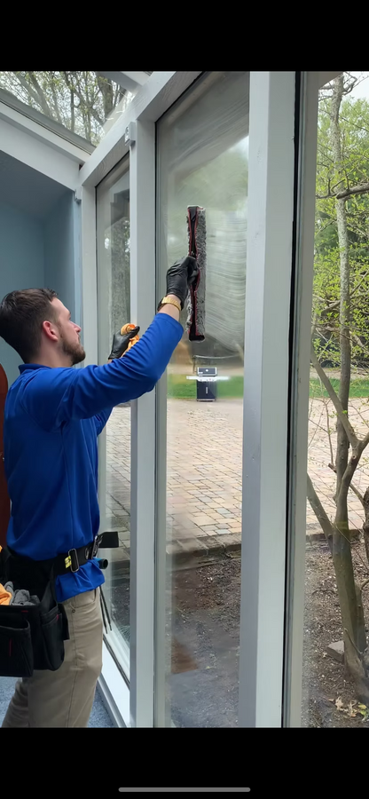 Person cleaning a window with a squeegee outside a building.