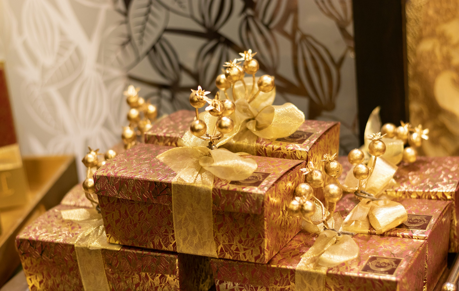 Decorative gift boxes with gold ribbons and bows on a patterned background