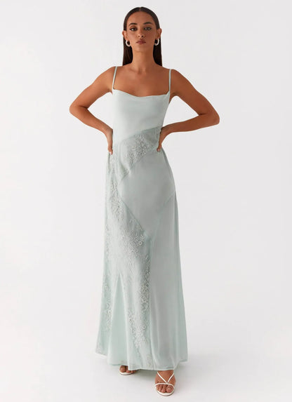 Woman wearing a light green evening gown with floral details on a white background