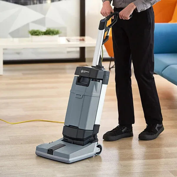 Person using a vacuum cleaner on a wooden floor in a modern living room.